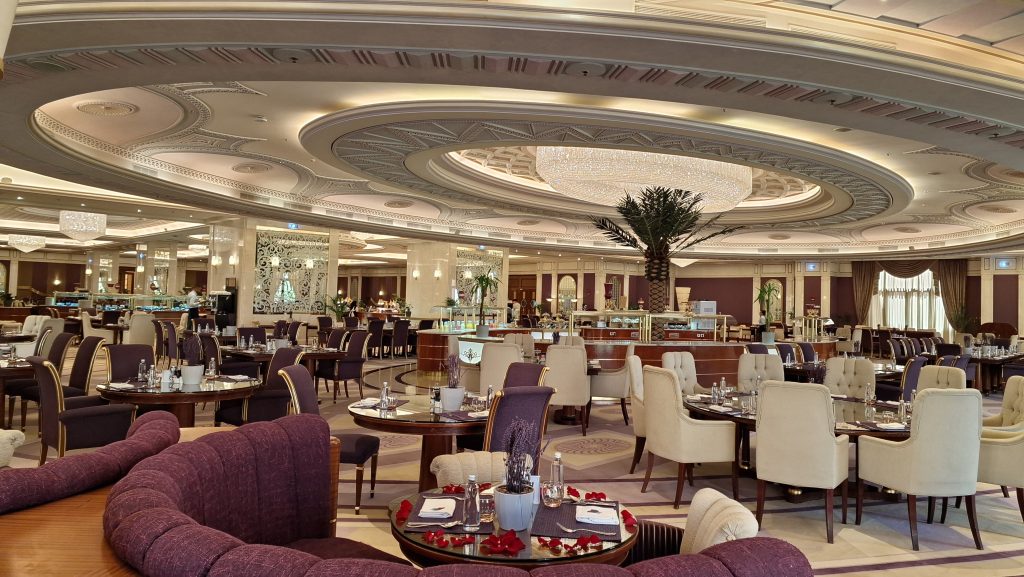 Elegant dining hall with circular ornate ceiling, chandeliers, and tables set for service in a luxurious restaurant interior.